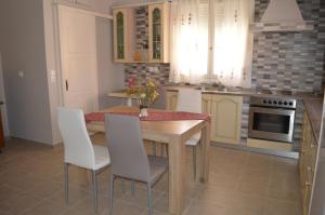 eine Küche mit einem Holztisch und weißen Stühlen in der Unterkunft Melissaratos Studios in Argostoli