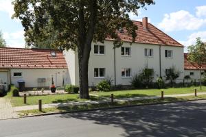 une maison blanche avec un arbre sur le côté d'une rue dans l'établissement goethe60, à Hohen Neuendorf