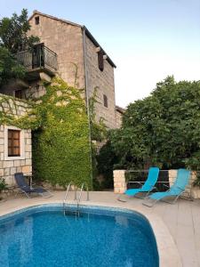 a swimming pool with two blue chairs and a building at Holiday home Villa Kastel in Korčula