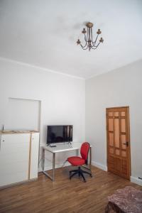 Cette chambre comprend une chaise, un bureau et une télévision. dans l'établissement Modern 2-room flat in the city center, à Šiauliai