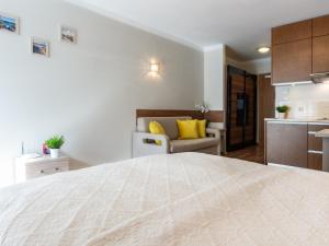 a bedroom with a large white bed and a couch at VacationClub - Villa Mistral Apartment 13 in Świnoujście