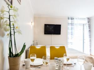a dining room table with yellow chairs and a tv at VacationClub - Villa Mistral Apartment 13 in Świnoujście