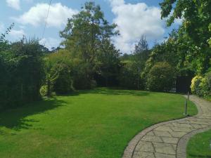 a grassy yard with a stone walkway at Thornham Cottage in Ivybridge
