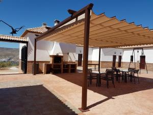 eine hölzerne Pergola mit Tischen und Stühlen auf einer Terrasse in der Unterkunft Apartamentos Rurales La Dehesa del Acebuche in Jaén