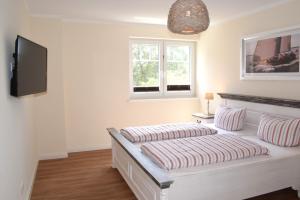 a bedroom with a bed with striped pillows and a television at Villa Ocean Time in Haffkrug