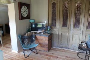 a living room with a tv and a chair and a clock at Dependance in Youx