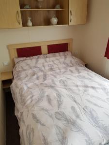 a bedroom with a bed with a white comforter at Caravan Willerby Gold Star in Looe