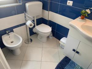 La salle de bains bleue et blanche est pourvue de toilettes et d'un lavabo. dans l'établissement Le Terrazze in Villa, à Reitano