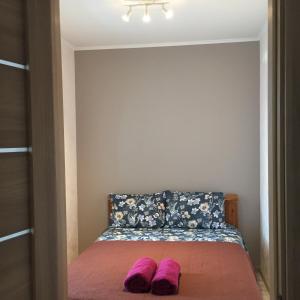 a bedroom with a bed with purple slippers on it at Cat Garden Deluxe Apartments Riga in Rīga