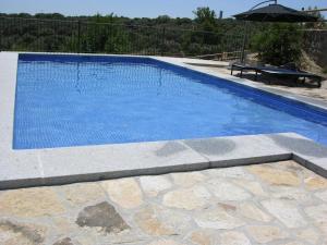 a blue swimming pool with a table and an umbrella at Apartamento Rural Albus Albi in Colmenar del Arroyo