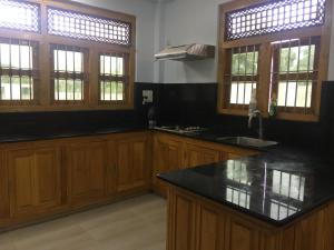 a kitchen with wooden cabinets and a black counter top at Ahi House in Kilinochchi