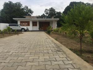 a house with a car parked in front of a driveway at Ahi House in Kilinochchi