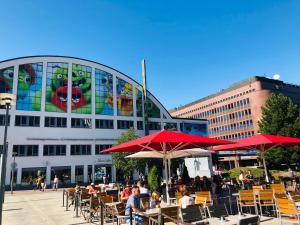 people sitting at tables with umbrellas in front of a building at Scandinavian Home in heart of Helsinki 26 in Helsinki