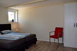 a bedroom with a bed and a red chair at Het Friese Landschap in Lemmer