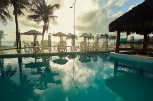 a swimming pool with chairs and umbrellas on the beach at Elegance Comfort Natal Beira mar Coberturas Vip in Natal