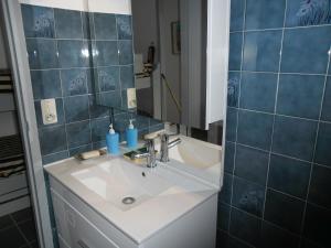 a bathroom with a sink and a mirror and blue tiles at les Huniers Appt 1er étage in Arcachon