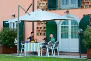 a family sitting at a table under an umbrella at Tenuta San Giovanni Lucca in Lucca