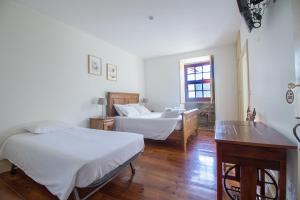 a bedroom with two beds and a desk and a window at Casa do Monte - Douro in Baião +74 photos
