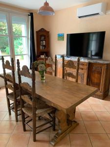 a dining room with a wooden table and a television at Villa Toulousaine in Grisolles