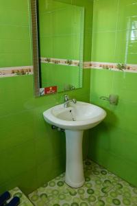 Baño verde con lavabo y espejo en Olina Hotel and Apartments Kampala, en Kampala