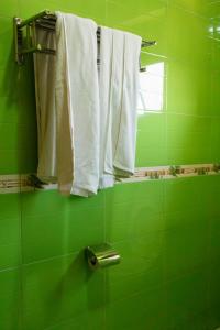 a green bathroom with white towels and a mirror at Olina Hotel and Apartments Kampala in Kampala