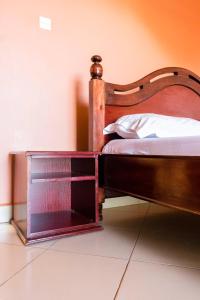 a bed with a wooden frame with a box next to it at Olina Hotel and Apartments Kampala in Kampala