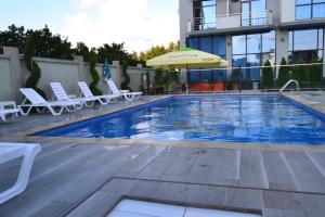 a swimming pool with lounge chairs and an umbrella at Hotel Skyline Batumi in Batumi