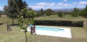 a swimming pool in a field with a tree at Cabañas Ayres de Sierra in Los Reartes