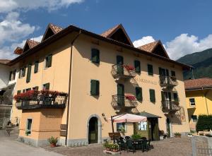 - un grand bâtiment avec une table et des chaises devant dans l'établissement Casa Mezzavalle, à Pelugo