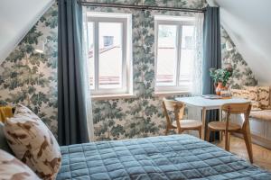 a bedroom with a bed and a table and windows at KaksTeist Apartments in Haapsalu