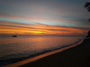 a sunset on the beach with a boat in the water at Areia do Atlantico Hotel in Porto Seguro
