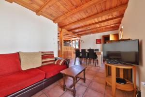 uma sala de estar com um sofá vermelho e uma televisão de ecrã plano em Le Chalet du Tanet spa sauna terrasse en Alsace em Soultzeren