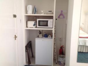 a small kitchen with a microwave on a shelf at The Clan MacGregor Room in Kilmarnock