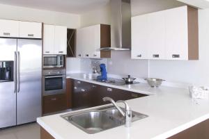 a kitchen with a sink and a stainless steel refrigerator at BonaireChoice Apartment in Kralendijk