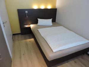 Bett in einem kleinen Zimmer mit einer weißen Matratze in der Unterkunft Apart-Hotel Wiesbaden in Wiesbaden