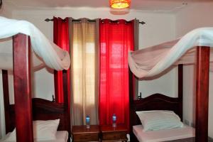 - 2 lits avec des rideaux rouges et blancs dans une chambre dans l'établissement Entebbe Vine Inn, à Entebbe