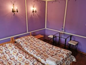 1 dormitorio con paredes de color púrpura, 1 cama y 1 mesa en Hadji Neikovi Guest Houses, en Koprivshtitsa