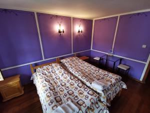 1 dormitorio con 1 cama con paredes moradas en Hadji Neikovi Guest Houses, en Koprivshtitsa
