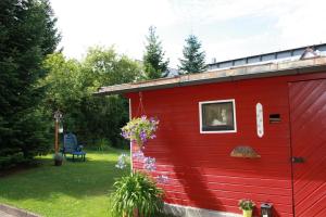 a red shed with a window and flowers in a yard at Haus Susanne in Oberhof