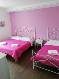 2 Betten in einem Zimmer mit rosa Wänden und Holzböden in der Unterkunft Diva Star Bol in Bol