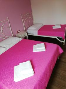2 Betten mit rosa Bettwäsche und weißen Handtüchern darauf in der Unterkunft Diva Star Bol in Bol