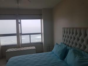 a bedroom with a bed and two large windows at Pam's Beach Flat in Amanzimtoti