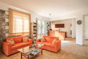 a living room with two orange chairs and a glass table at Hotel Aphrodite in Stoupa