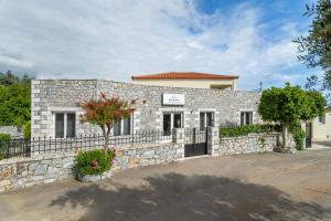 a stone building with a fence and a tree at Hotel Aphrodite in Stoupa