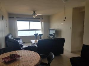 a living room with couches and a table and a tv at Pam's Beach Flat in Amanzimtoti