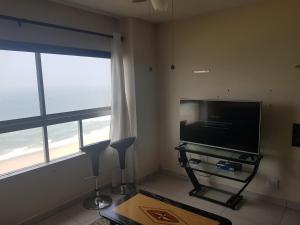 a living room with a flat screen tv and two windows at Pam's Beach Flat in Amanzimtoti