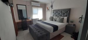 1 dormitorio con 1 cama grande y espejo en The New Mall Guesthouse en Maun