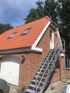 a brick house with a staircase leading to a garage at Ro i skoven - men tæt på byen in Varde