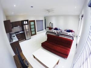 a living room with a red couch and a kitchen at En el Centro 1 Hermoso Lof't Familiar AC WiFi 300 mbps in Aguascalientes