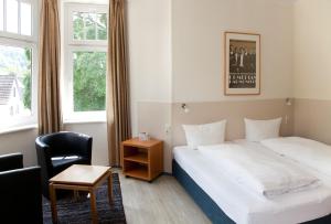 a hotel room with a bed and a chair at Hotel Weidenhof in Plettenberg